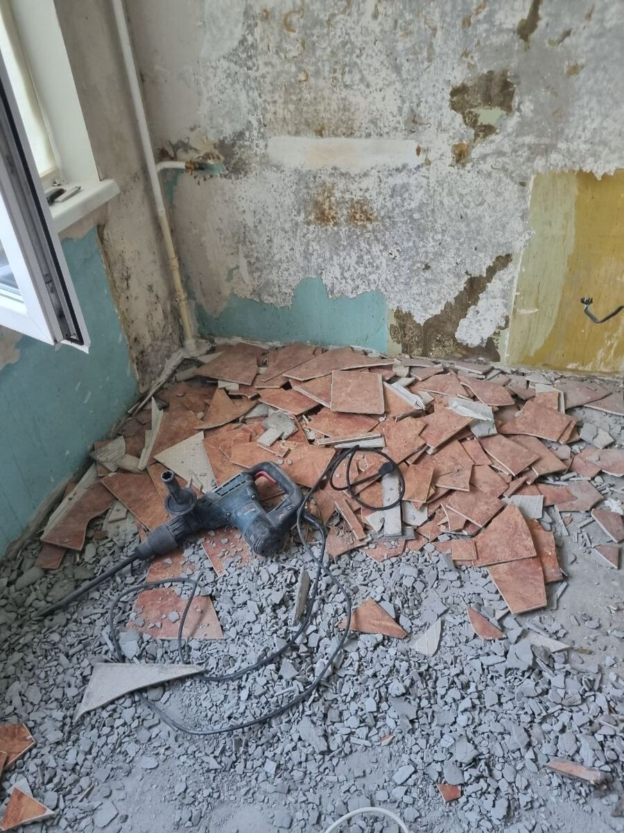Сбитая плитка и мусор на полу ванной во время демонтажных работ