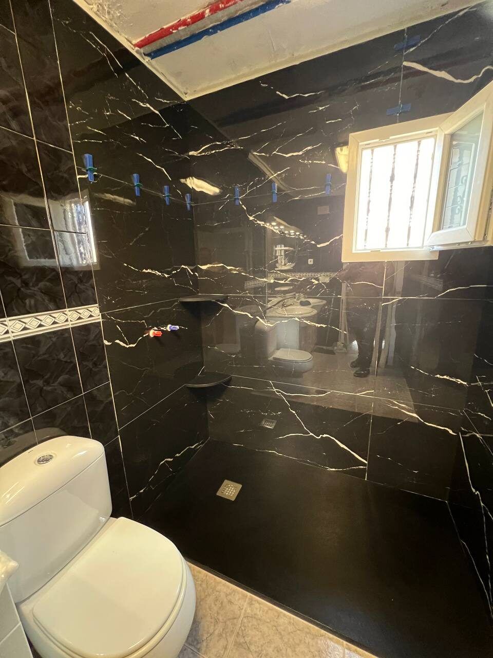 The same bathroom after renovation - black marble tiling and new fixtures