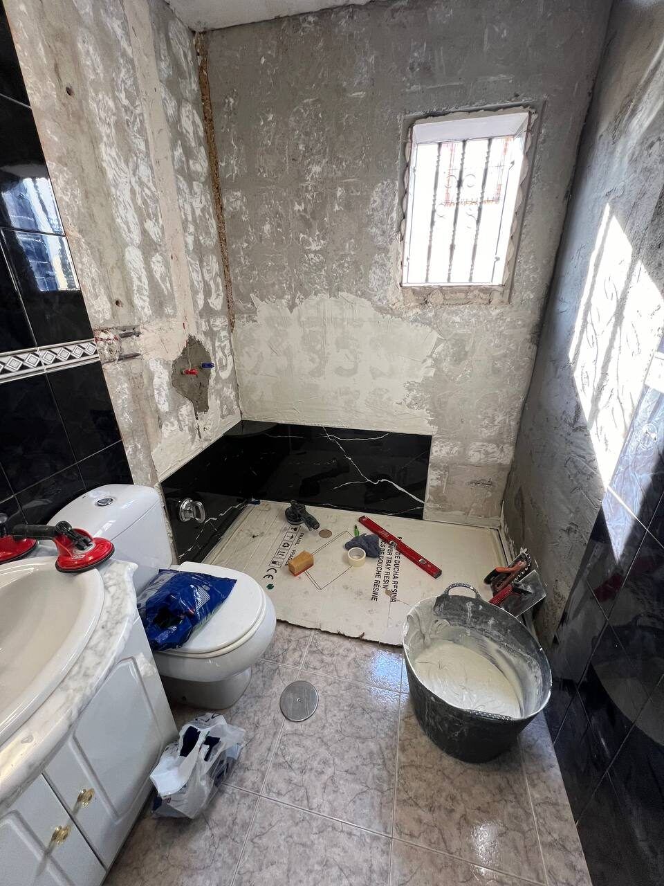 Bathroom before renovation - stripped tiling and old fixtures
