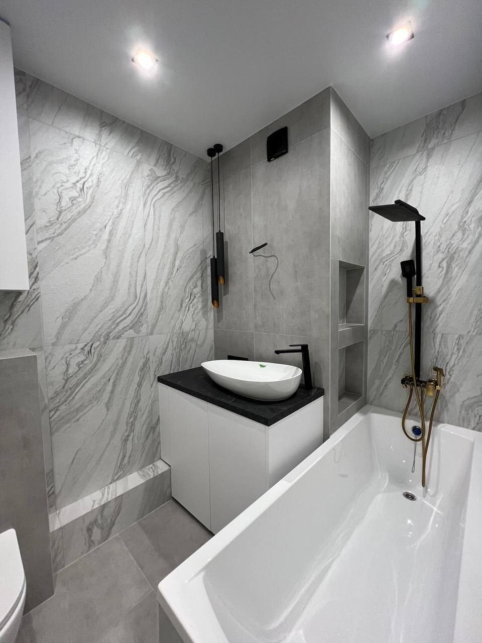 Black marble bathroom with gold taps after renovation