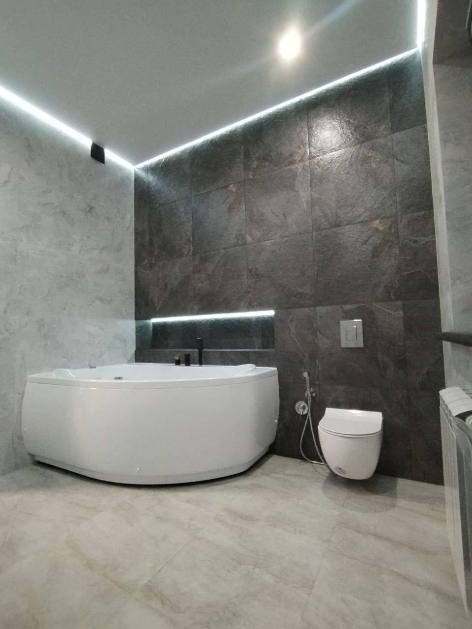 Corner whirlpool bathtub in a bathroom with grey stone tiling