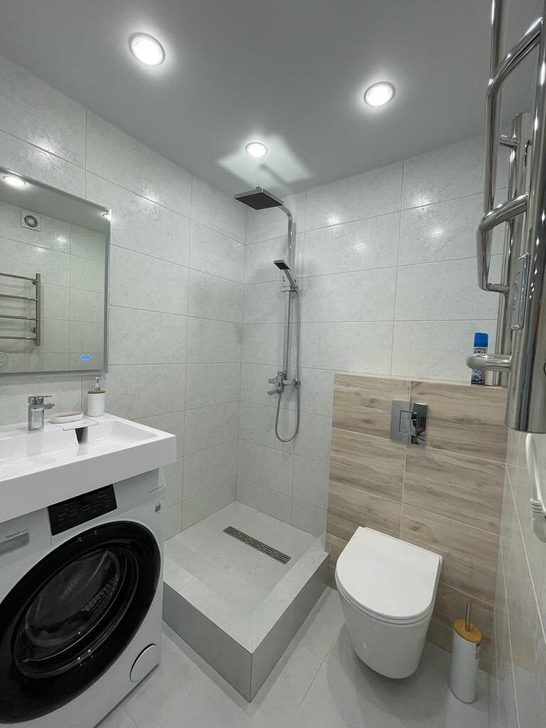 Shower with wood-effect tiling and a washing machine in a renovated bathroom