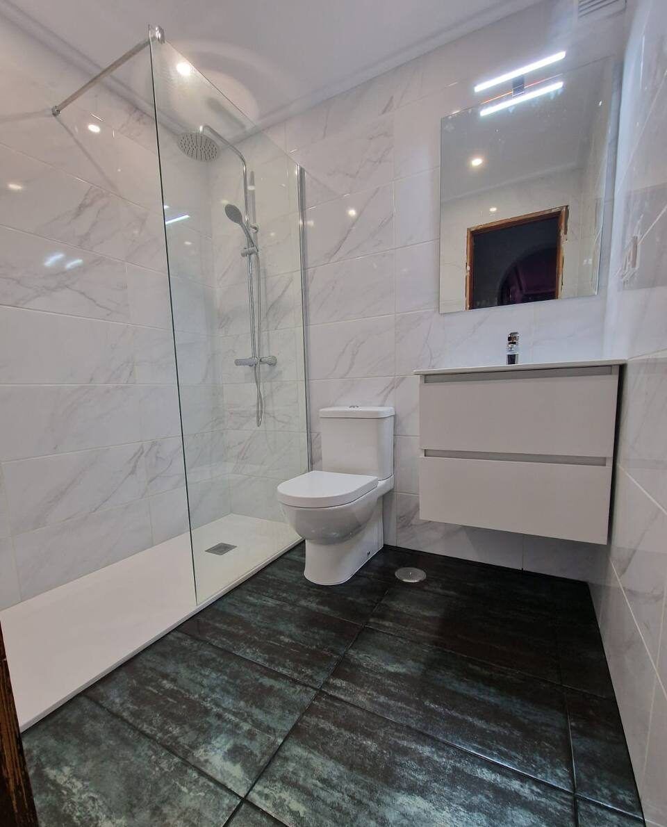 Walk-in shower with dark floor tiles and white marble walls