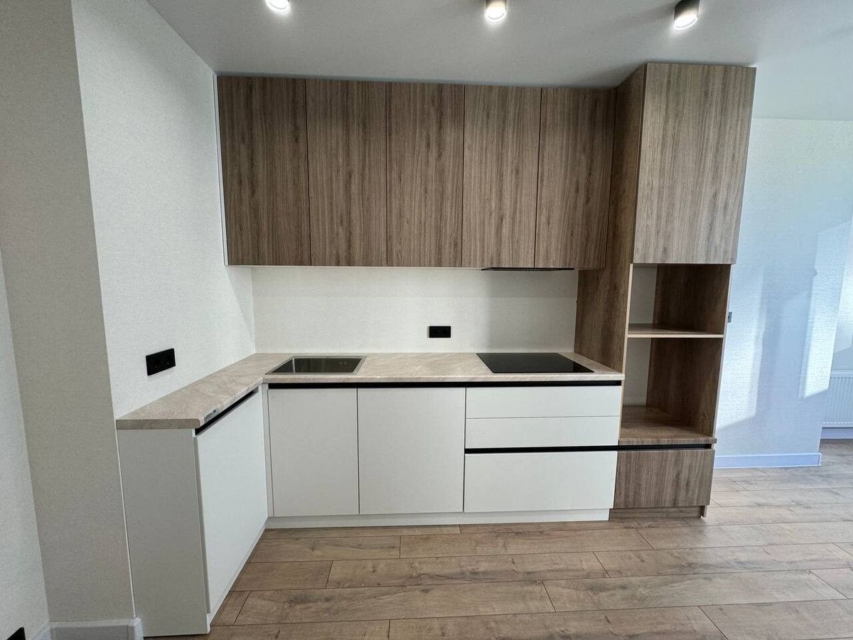 White kitchen with tall cabinets and wooden details in a renovated flat