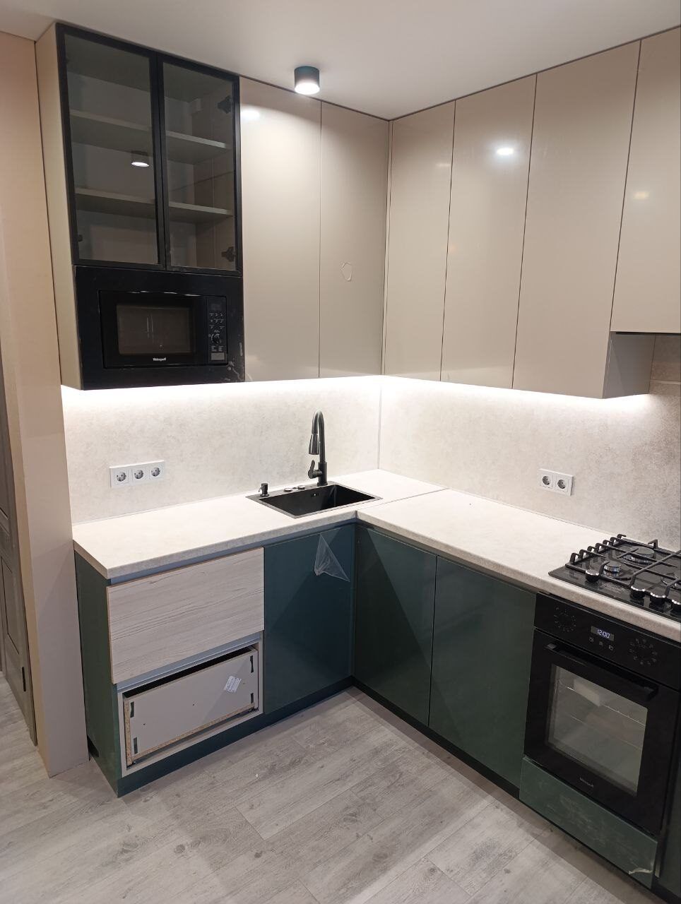 Green kitchen with a black worktop after a flat renovation