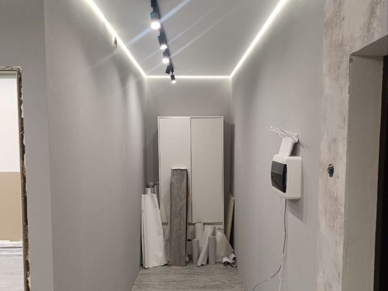 Hallway with an LED strip in the ceiling recess and track spotlights