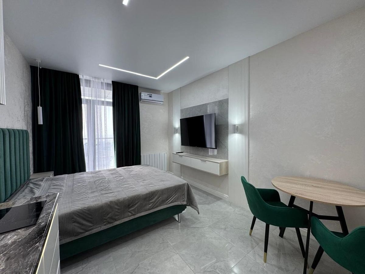 Dining table with green chairs next to the bed in a renovated studio apartment