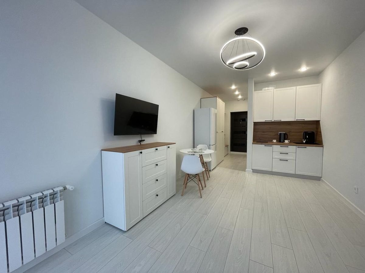 Kitchenette with white units and a wooden worktop in a renovated studio