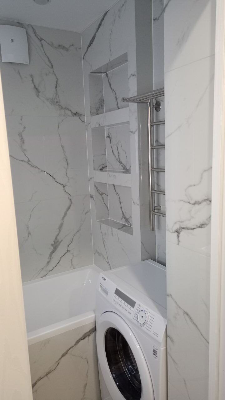 Washing machine built in under the counter in a renovated marble bathroom