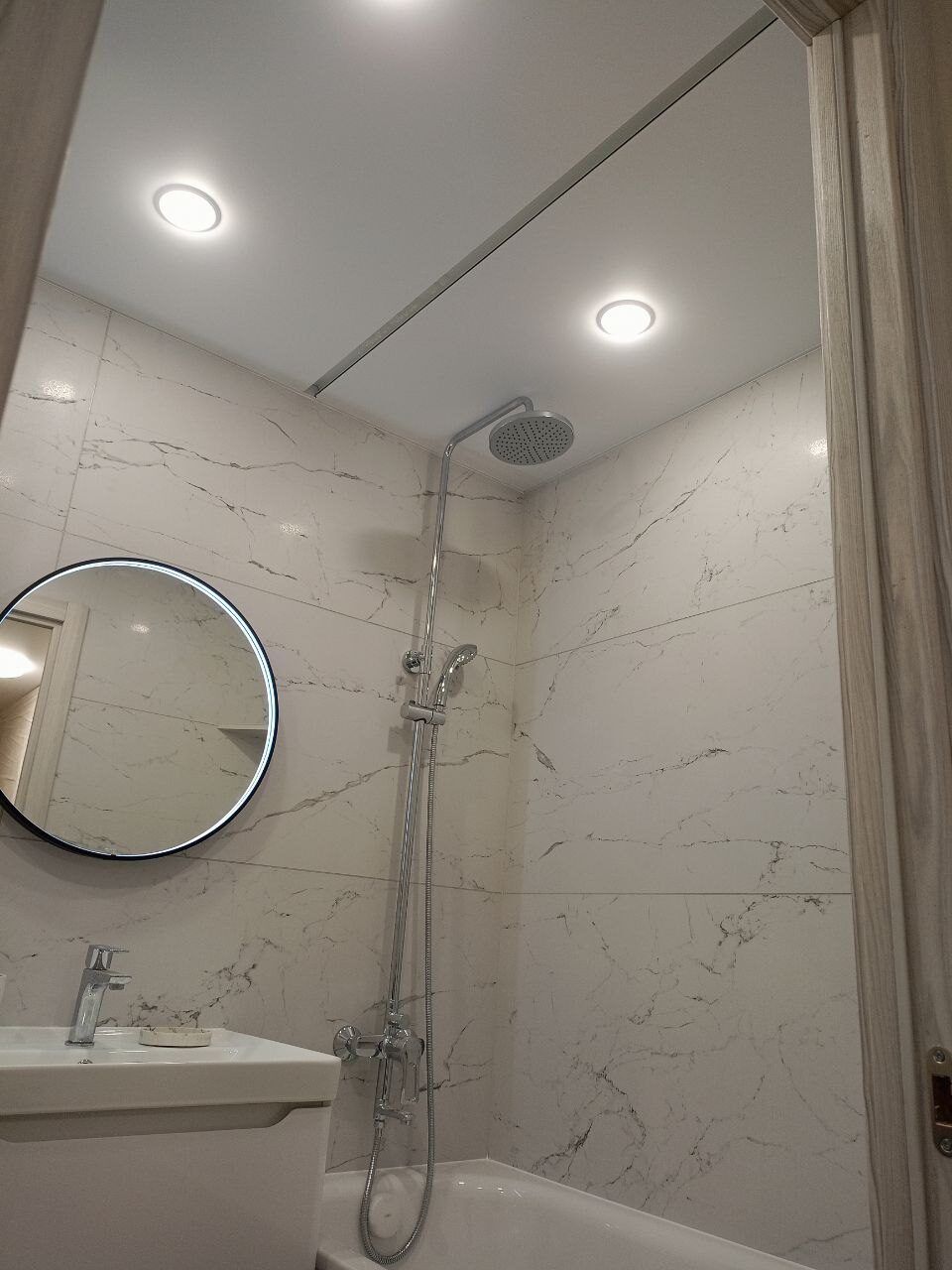 Glass-screened shower and a round mirror after a bathroom renovation