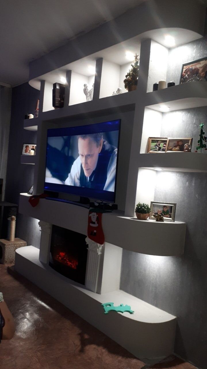 Finished TV wall with backlit niches and an electric fireplace
